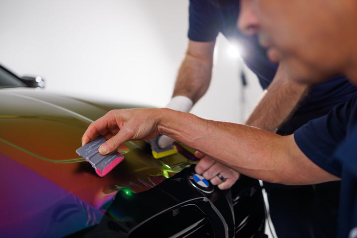Installer using pink Monkey Strips to wrap a BMW